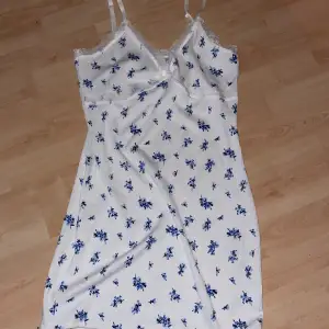 En vit klänning med blåa blommor som är ribbad och bra passform