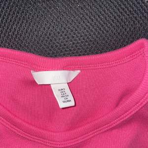 Ett kortare linne med stark rosa färg som är ribbat. 