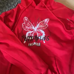 En röd hoodie med tryck av en fjäril framtil. Aldrig använt 