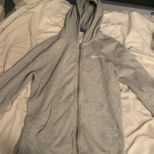 Champion hoodie grå - Säljer denna champion hoodien eftersom den har blivit för liten för mig och använder inte den mer.  Skön hoodie med dragkedja med, skön luva. Inga skador eller fläckar på den. 
