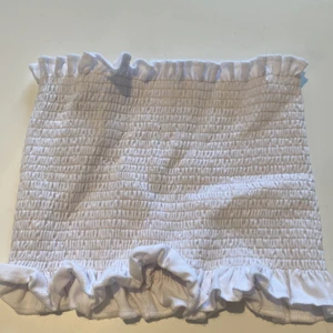 CROP TOP/BANDLÖS TOPP - Säljer nu min croptop i färgen vit. Den är i jätte stretchit material och passar XXS-S skulle jag säga. Passar M också då den är stretchig men inte större. Volang på sidorna och nyskick. 