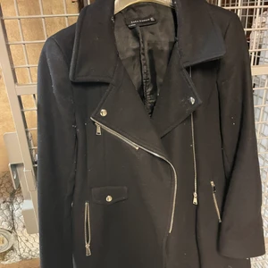 Svart kappa från Zara Woman - Svart kappa i fint skick från Zara. Den har en asymmetrisk dragkedja och två fickor. Använd men i fint skick utan hål i foder etc.