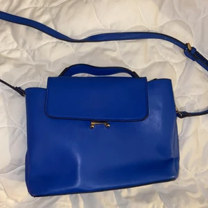 Blå axelbandsväska - Blå axelbandsväska i skinnimitation från Mango. Gulddetaljer.