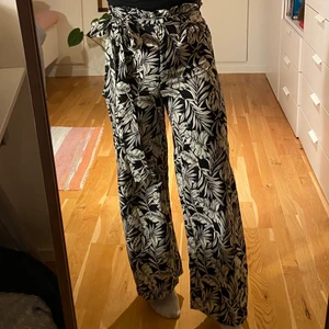 Mönstrade byxor - Mönstrade byxor med knytning i midjan, svart/beiga med palmblad. Från MANGO strl xs, jag är 165cm. Tunt och skönt tyg. 