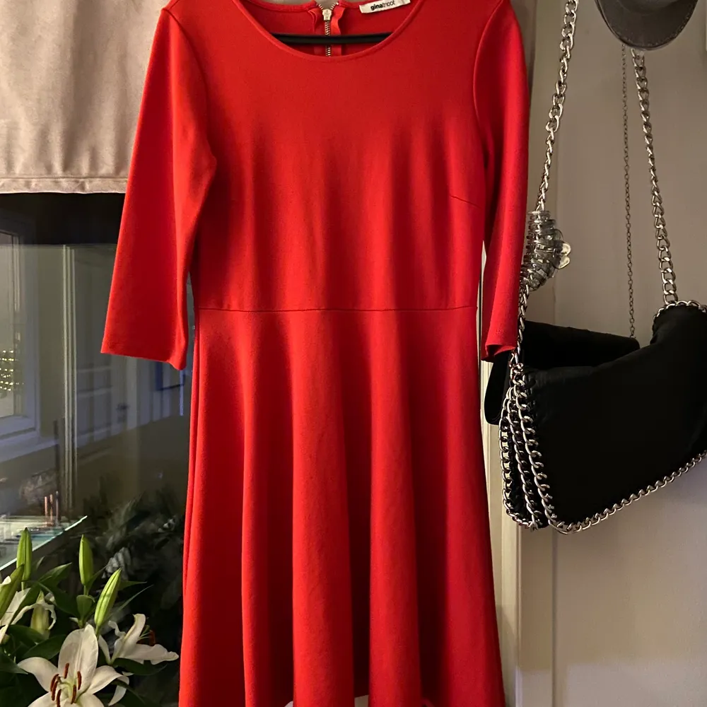 En röd klänning med volang från midjan, armar till armbågarna och str.M . Klänningar.
