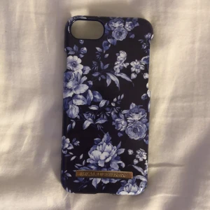 iPhone 7/8 - Ett fint blått blommigt skal som passar iPhone 7&8. Det är en liten spricka uppe vid kameran som drar ner priset (inget som syns när skalet är på!)
