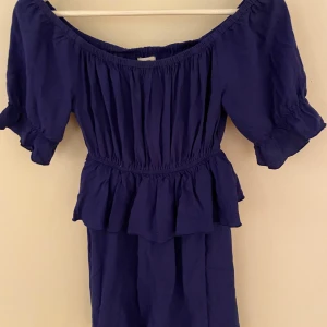 Blå klänning  - En jättefin blå klänning. Använd en gång så i ett bra skick. Fina volanger och formar kroppen fint.