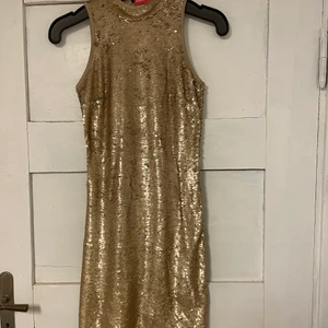 Guldig paljettklänning  - Guldig paljettklänning med dragkedja i bak i storlek XS . Aldrig använd med prislapp kvar. Köpt i lite sämre skick se bild 3. Budgivning startar på 60 kr i komentarsfältet köp direkt för 100 kr! (Budgivningen avslutas 1 april)