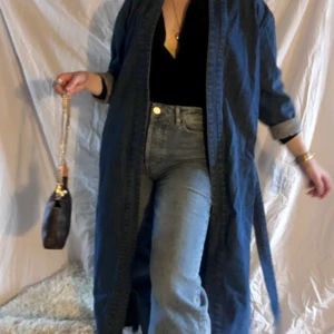 Blå jeanskappa från NA-KD - Lång och fin jeanskappa från NA-KD, använd någon enstaka gång så den är i jättefint skick. 🌹💕👏🏻✨