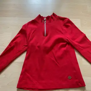 En röd tröja med dragkedja högst upp från kaphal i storlek 146-152. Väldigt fint skick och tvättas innan den skickas. !! Köparen står för frakten!!