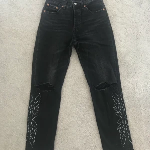 Svarta Levi’s premium - Svarta jeans Levi´s premium modell 501 med nitar och "trasiga" knän, fransiga kanter nedtill, stl W 25 L 28, 300 kr (nypris 1000 kr i New York)