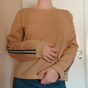 Ljusbrun tjocktröja - Tröja med svartvita band på ärmarna. Det finns en liten ljus fläck på framsidan men den är ganska diskret. Säljer för att det inte är min stil längre. Köparen står för frakten men jag möts gärna upp i gbg också😊🤎