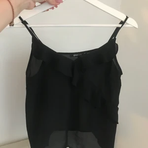 Svart volanglinne! - Linne från Gina Tricot! Super skick, helt som ny. Storlek 34 men reglerbara band. Frakt tillkommer! Finns kvar tills den markerats som såld.🤩🖤