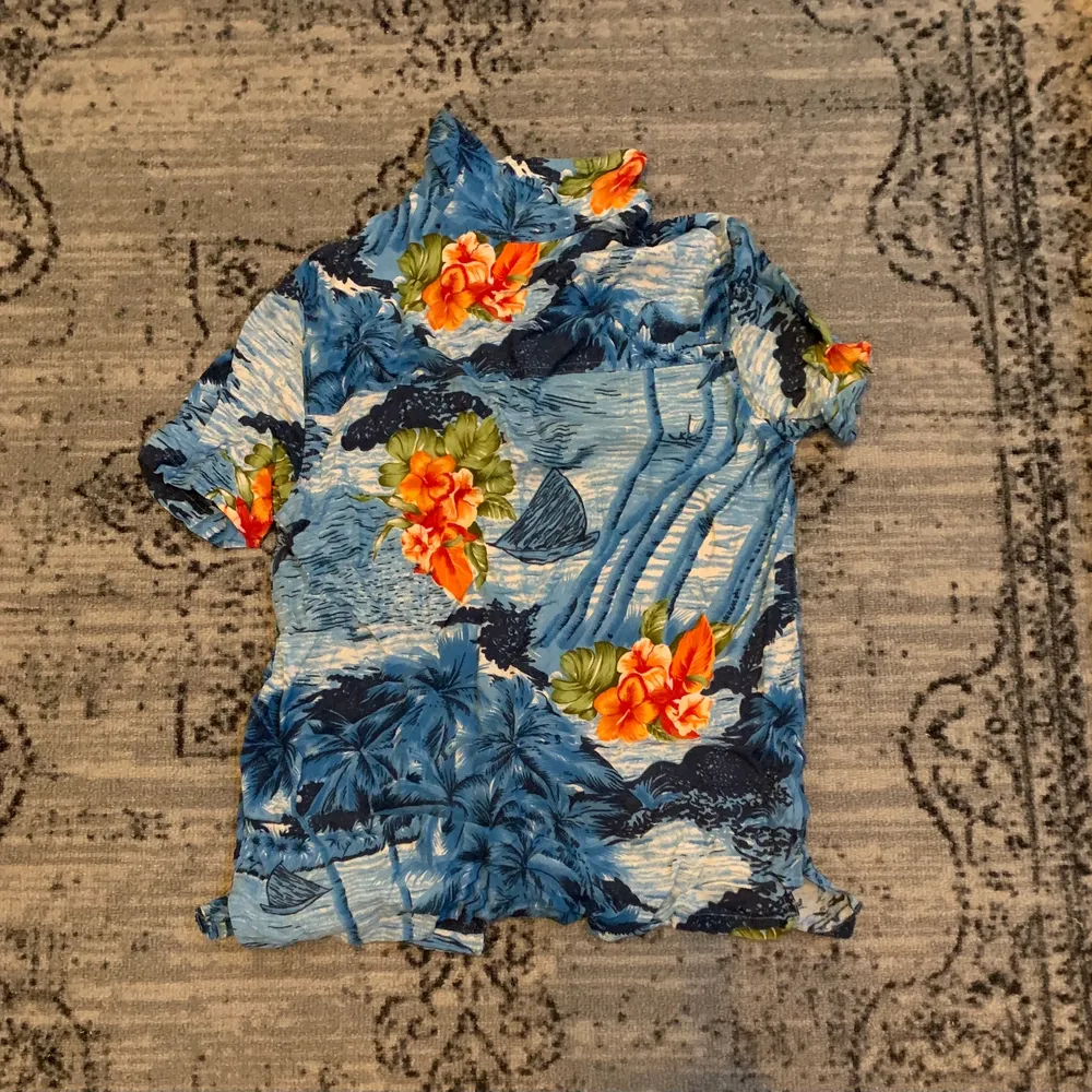En blå hawaiiskjorta med blommor, och diverse, på. Köpt secondhand för ett drygt år sedan, aldrig använd. 🌊🌼. Skjortor.