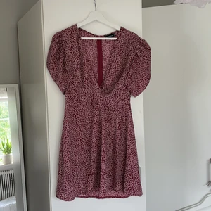 Blomning klänning från PrettyLittleThing - Vinröd klänning med små vita blommor. Klänningen är helt oanvänd. Den är i storlek 38 men skulle säga att den är liten i storleken så passar definitivt en 36 (jag brukar ha strl 36 så skicka meddelande om ni vill se hur den sitter på) passar med största sannolikhet även en 34