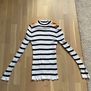 Randig tröja med orangea axlar - Randig tröja med orangea axlar. Storlek L. Hög krage.