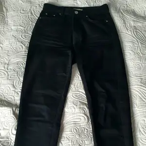 Svarta Dagny mom jeans från Gina Tricot. Använda vid endast 2 tillfällen. Affärens beskrivning: Mom Jeans utan stretch med normal passform. Jeansen är svarta och har en hög midja. De är gjorda av Denim och har en dragkedjegylf och avsmalnande byxben med en ankellång benlängd.