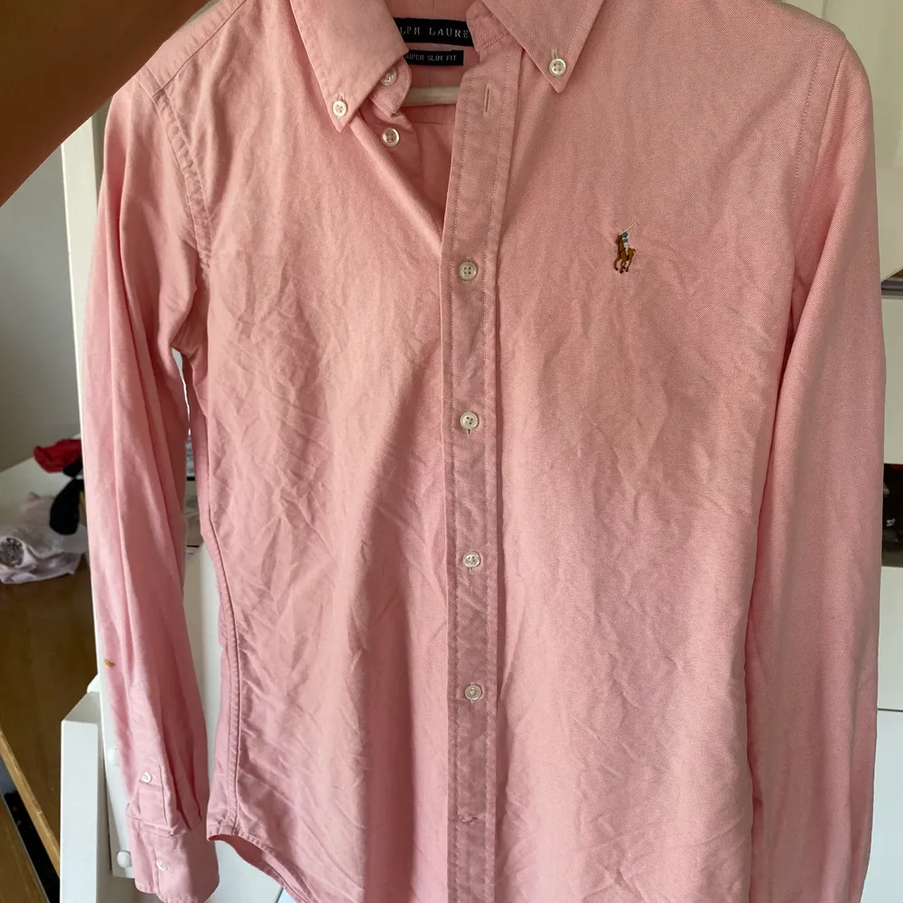 Ralph Lauren dam skjorta i rosa färg. Super slim fit i storlek 6, vilket motsvarar xs/small . Liten färg fläck på armen. Ord pris 1200 kr. Skjortor.