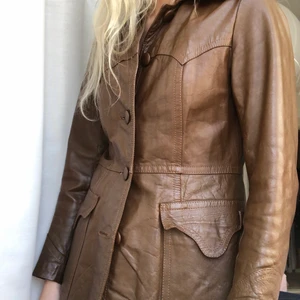 Vintage läderjacka 32-36 - Säljer brun läderkappa/kavaj/jacka i storlek 32-36. Jag är normalt en 36:a så lite liten i ärmar om man vill ha plats med en tröja under!  Slutar precis på stussen (168cm)Fint skick. Bara ett litet slitage hål uppe inne i jackan vid krage. Se sista bild. Annars helt intakt. Fina detaljer och så fin brun färg✨  Upphämtning Lund eller köpare står för frakt ca 99!