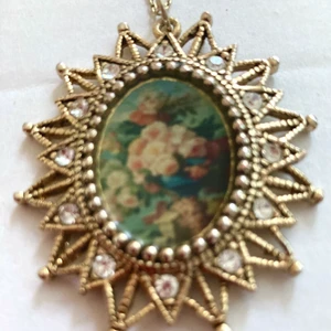 Hänge - Hänge med blommotiv , gulmetall , nickelfri . Kristaller o stenar . Höjd 2.7cm bredd 2 cm . 