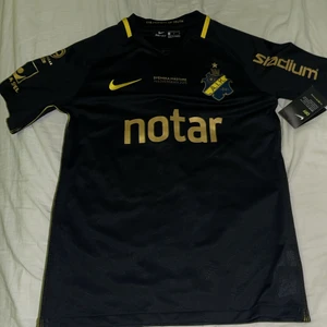 Nike AIK Revolutionatröja/T-shirt med guld tryck - Jag säljer en aik tröja som är oanvänd, den är i storlek M. Kan mötas upp inom Sthlm eller frakta (köparen står för frakten)