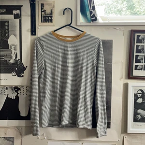 Randig tröja   - Grå-vit randig långärmad tröja med gul ringningskant. Det står storlek 10 vad det nu översätts till. :) 