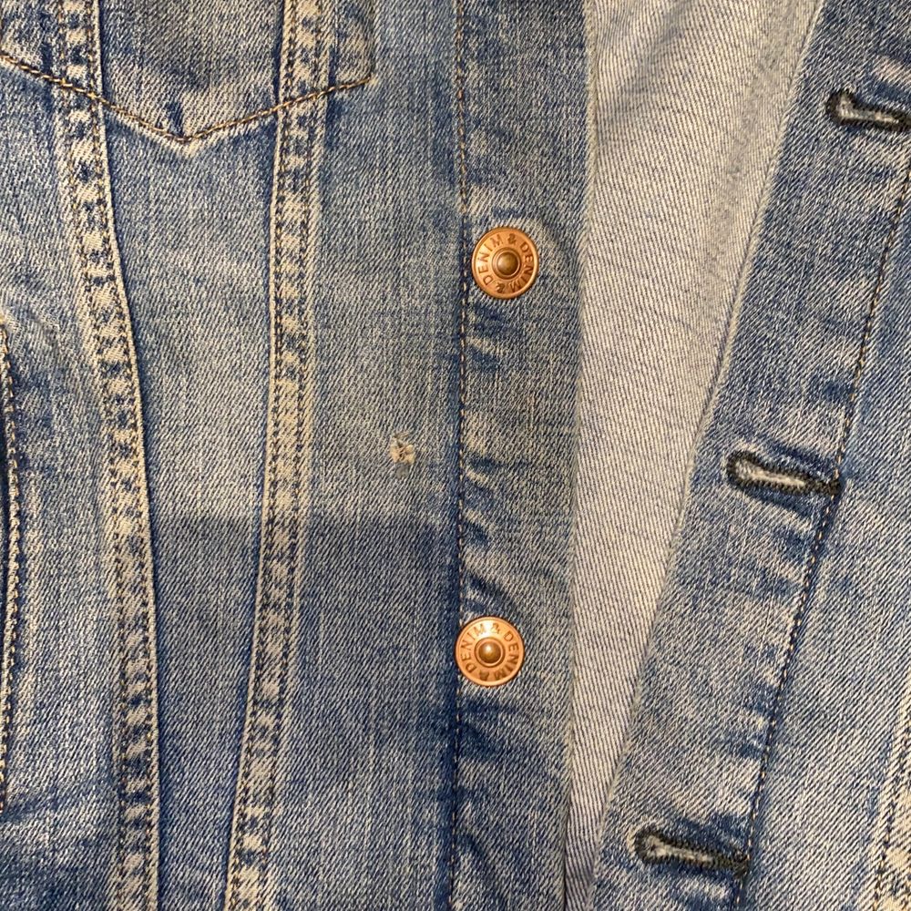 En mellanblå jeansjacka med bronsfärgade knappar. Ett litet hål som är sydd. Syns knappast när jackan är på. Kontakta gärna vid frågor eller köp :) . Jackor.