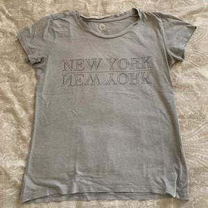 Skön grå t-shirt från Cubus. T-shirten har ett tryck på bröstet där det står ”New York”. Den är perfekt till vardagen! Köparen står för frakten. Kan även mötas upp i Malmö.