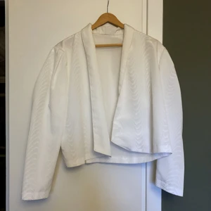 Retro blus med puffärmar S-M - Vacker blus/kavaj med subtilt mönster i väven. Puffiga axlar och öppen fram. Tänker fint att knäppa med en brosch. Tyget är av det grövre slaget, ev siden?   Storlek funkar på S-M ungefär 