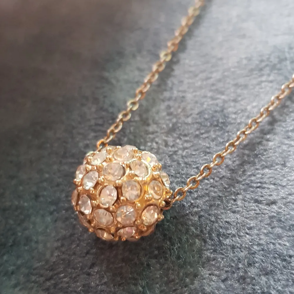 Guldigt halsband med diamanter. Halsbandet är 52 cm allt som allt och bollen är ca 1,2 cm i diameter. (Ej äkta guld/ diamanter). Accessoarer.