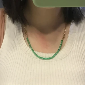 halsband - Ett fint pärl halsband gjord på elastisk tråd och gröna pärlor, en kedja där bak med fina detaljer.