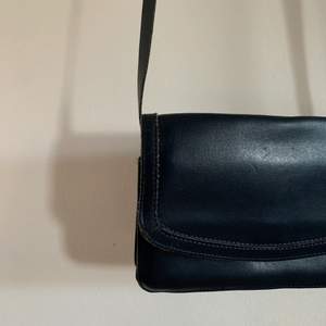 Mörkblå (färgen är svår att se på bilden) handväska med långt, justerbart axelband. Tre fack innuti, ett med dragkedja. Mått: 20x14x4 cm (djupet går att förstora) Axelbandets mått: va 110cm🌟