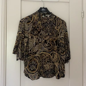 Blus från HM - Snygg mönstrad blus från HM. Blusen är i bra skick då den är endast använd ett fåtal gånger. Vid ärmarna finns det en snygg knyt detalj. Blusen gör sig inte helt rättvis på bild men ärmarna är i armbågsläng. 