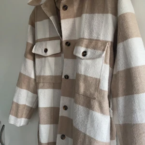 Rutig beige kappa - Denna beiga kappan är i nyskick. Inte alltför tjock i materialet.