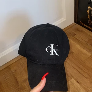 Calvin Klein Keps - Svart justerbar CK keps köpt på Zalando. Kommer aldrig tillanvändning för mig därför säljer jag den. Lite dammig bara som jag fixar till den säljs. Ny skick.