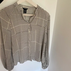 Blus  - Svart vit mönstrad blus med ballong ärmar. 