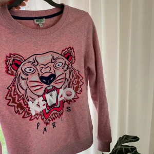 Kenzo  - Rosa kenzotröja i storlek S. Färgen är rosa med lite grå/blå i. Trycket är i silver, blå och rosa. Super snygg till vita byxor eller vit kjol, även snygg till mörkare jeans!!  Köpt för 1200kr för ca 3 år sedan. 