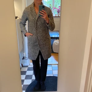 Vinterkappa 40% ull - Gråmelerad. Ganska rak i formen. Jag är numera M så denna är för liten för mig. Ytterplagg 60% polyester och 40% ull. Foder 100% polyester. Skickas inte. Kan mötas i centrala Stockholm. 