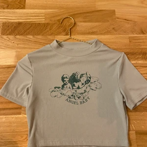 Crop top ”angel baby”  - En grön crop top med motiv och texten ”Angel Baby”. Säljer då den inte kommit till användning, endast provad. 