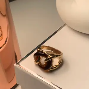 En guldig ring med bruna ditaljer i storlek M!💍☺️💍 buda! (Kan skicka men köparen står för frakt;)