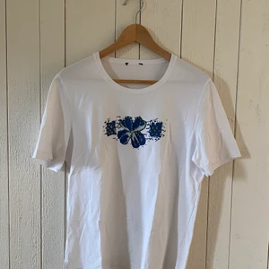 T-shirt med paljettmönster - Vit t-shirt med blåa blommor i paljetter. Passar som storlek M. Märke är okänt. Mycket bra skick.