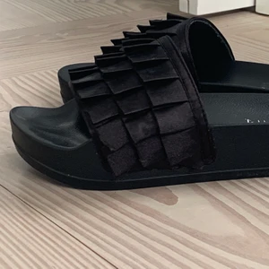 Duffy tofflor med volanger - Ett par superfina svarta tofflor med volanger från Duffy i nyskick! Användt endast nån gång pga för stor storlek för mig. Strl 38, köparen står för frakt. Skriv privat om du är intresserad eller för mer info🤎🤎🤎