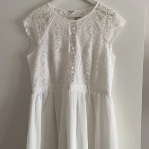 Studentklänning från Nelly - Vit studentklänning från Nelly. Köpt våren 2020 men aldrig använd. Prislapp är kvar. Storlek 44.