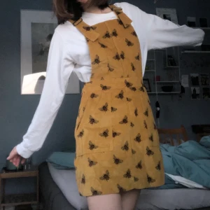 Manchester hängsle klänning - En jätte fin manschetter hängsle klänning med bi motiv på. Köpt på en liten butik i Edinburgh för 3 år sedan. Märket heter Run&Fly. Har aldrig använt den mer än att prova den. Jätte fint kvalete. Dragtjedja vid midjan och hängslena är justerbara. Säljer pga att den inte kommer till användning. Köparen står för frakten ✨