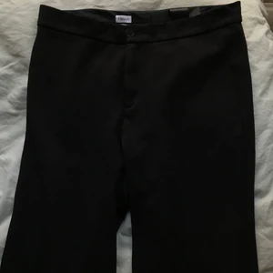 Filippa K kostymbyxor strl L - Svarta byxor från Filippa K. Upplagda, fint skick! Mjukt tyg/stretchigt tyg, utan fickor fram eller bak. Strl L men funkar för M. 