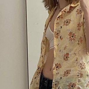 Blommig skjorta - Gul kortärmad skjorta i blommigt tyg, oklart vilken storlek men jag är xs för preferens så den passar nog stötte personer än mig med eftersom den är  oversized på mig:)