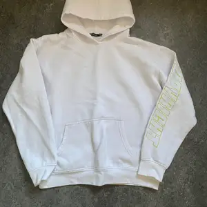 En vit hoodie med ”neon” grön text på vänster arm. Har används! Passar M/S
