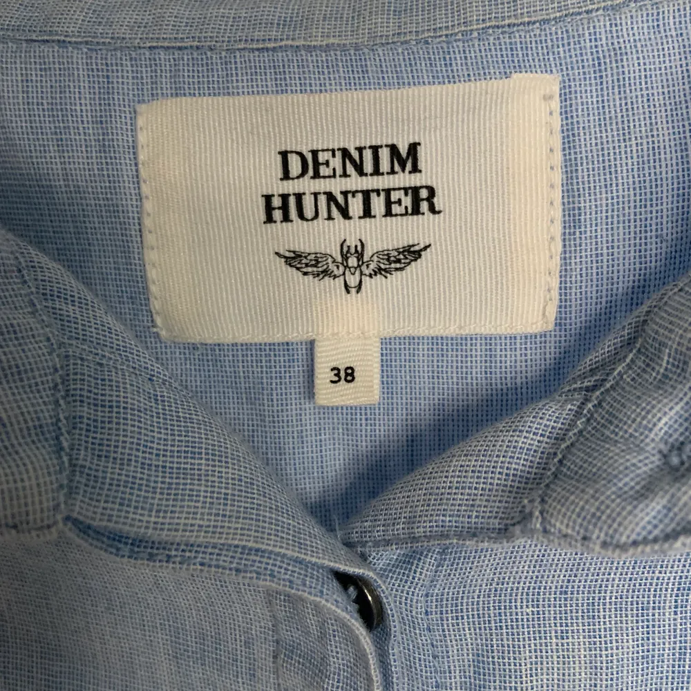 Blå skjorta från Denim Hunter i storlek 38. Använd en gång. Finns brodering vid ärmslutet på båda armarna (se bild. Ordinarie pris 750. Skjortor.