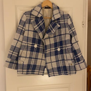 Rutig Kavaj/jacka - En as cool rutig kavaj/jacka som är fodrad. Vita knappar, från märket Morris lady Sample, kort i modellen, slutar lite över rumpan och har flared armar. Producerades endast en, vilket är denna. Blå vit.