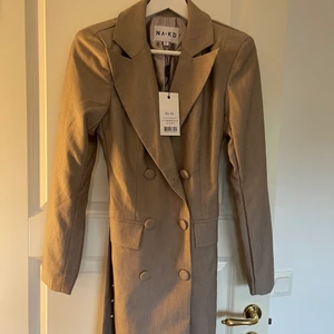 Blazer - Blazer från nakd med bälte i midjan, helt oanvänd. Storlek 34/xs. Funkar att ha som klänning